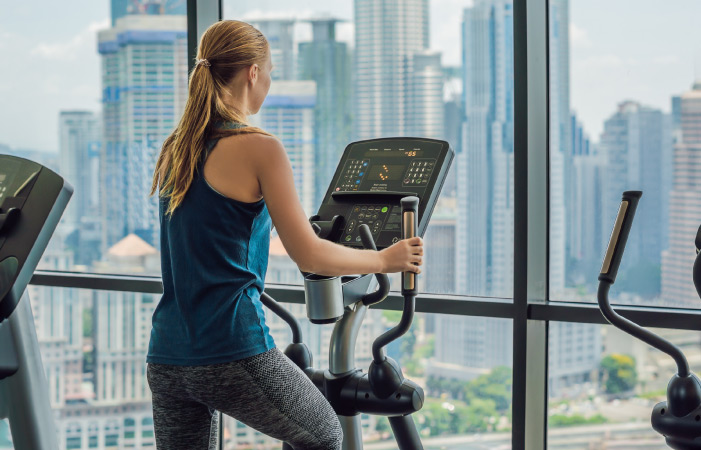 Woman exercising on an elliptical with a city view