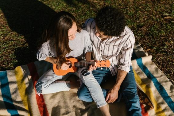 Happy couple having a picnic and playing music.