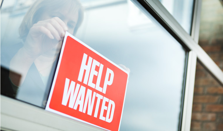 A woman putting up a help wanted sign