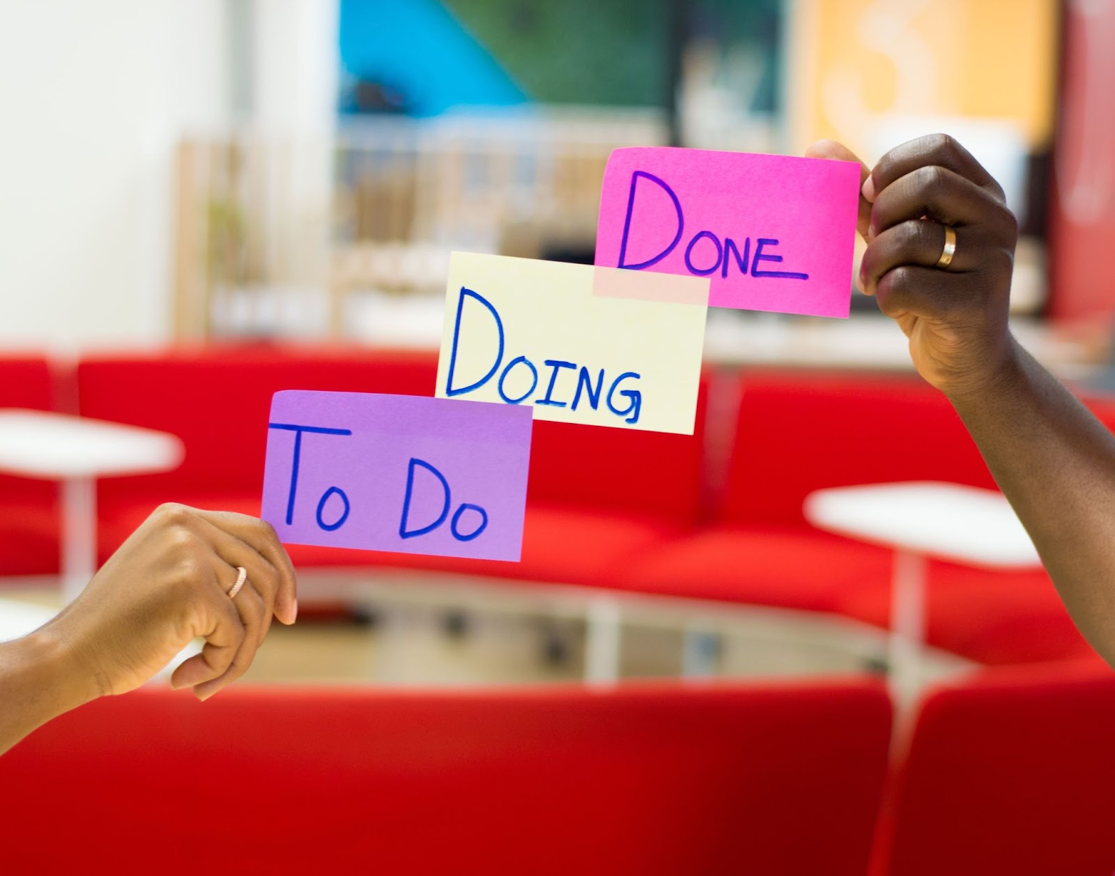 Hands holding up post-it notes with: "to do, doing, done" written on them.
