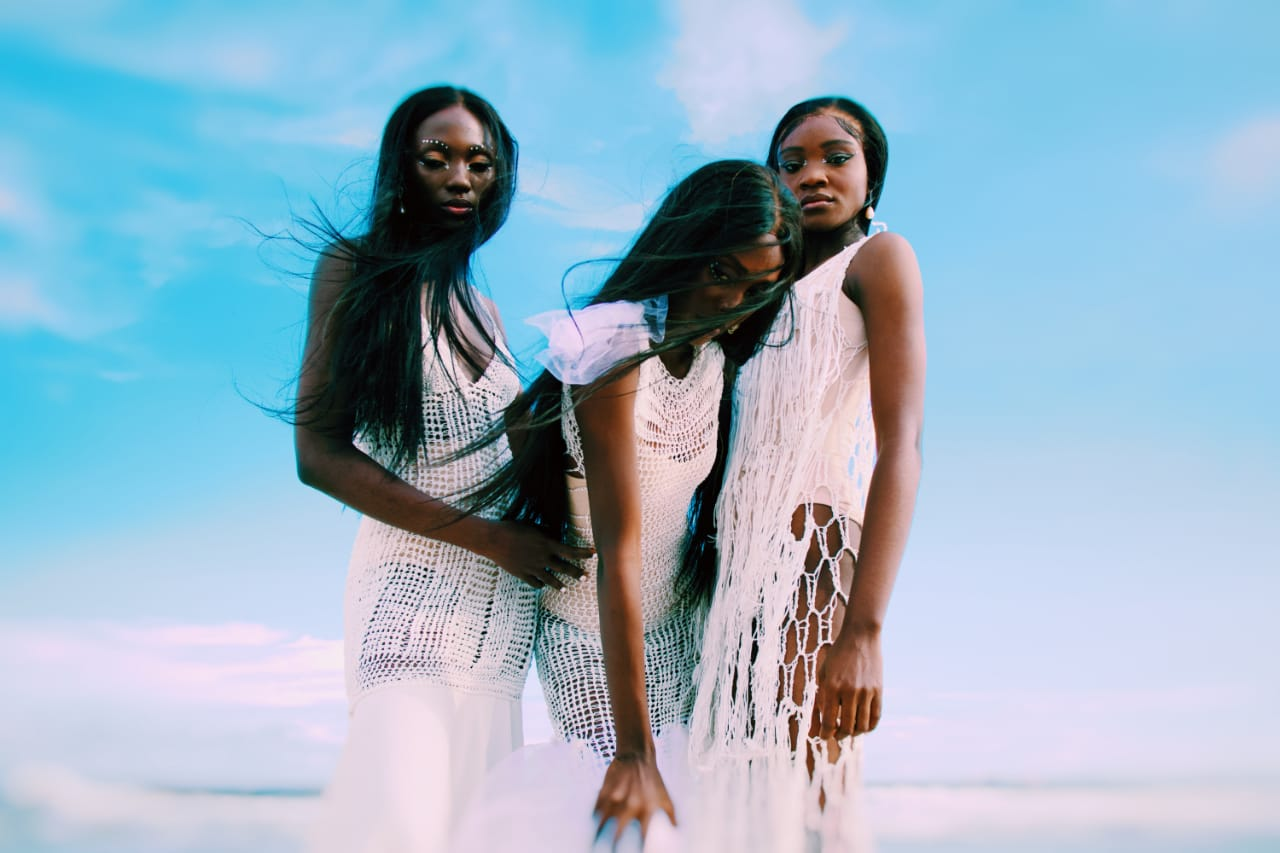 Female models wearing crocheted dresses running by the beach as featured in Pink Noise: a fashion film