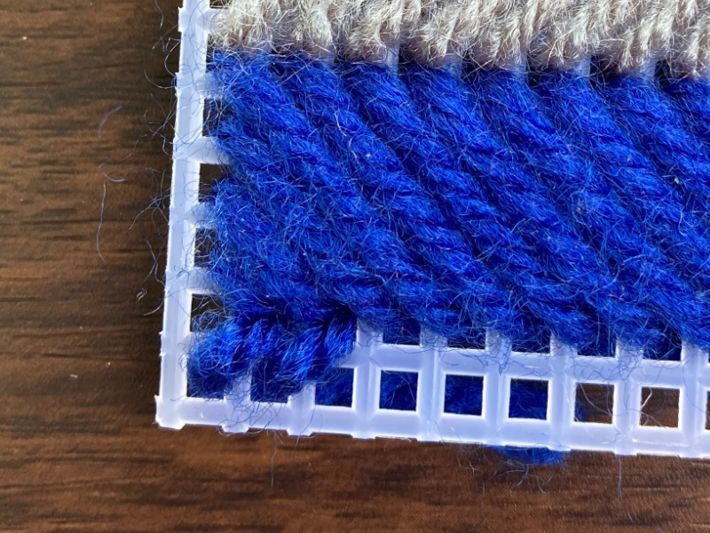 making a diagonal stitch on plastic canvas using blue colored yarn