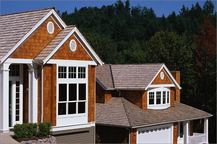 WeServe brick house with wooden shingles on the roof with background of trees