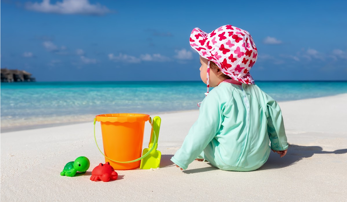 baby playing on the beach with the essential beach packing list