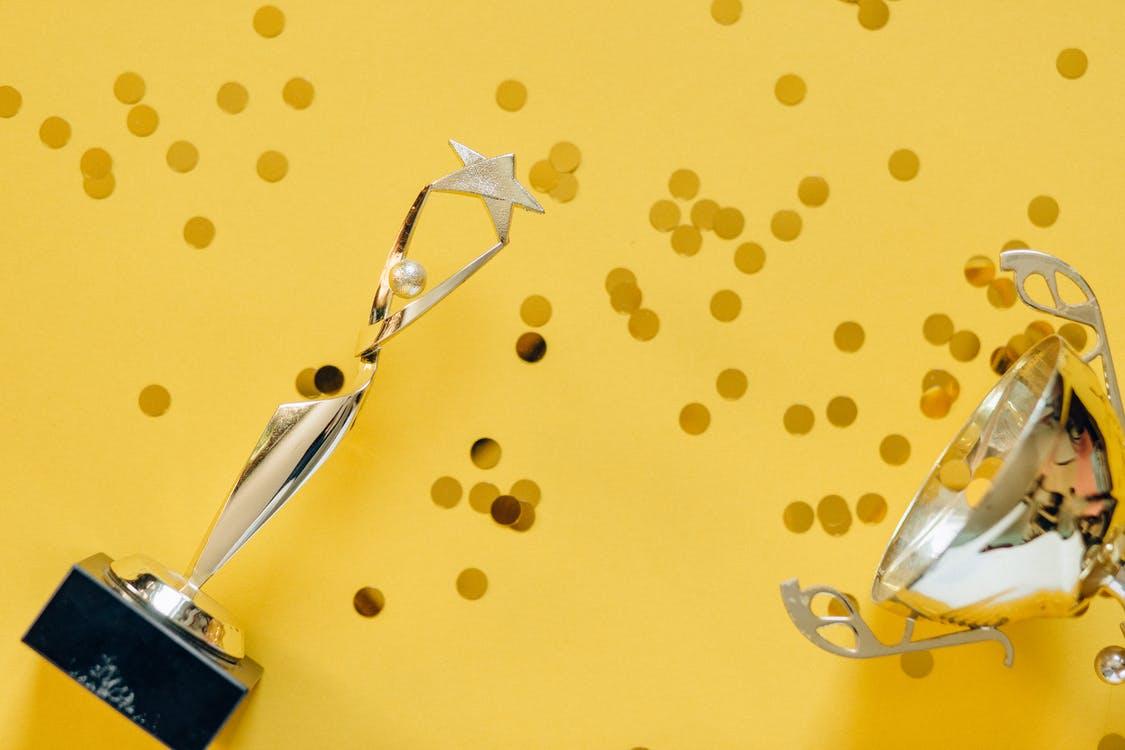Two trophies lying on a yellow background with gold circles