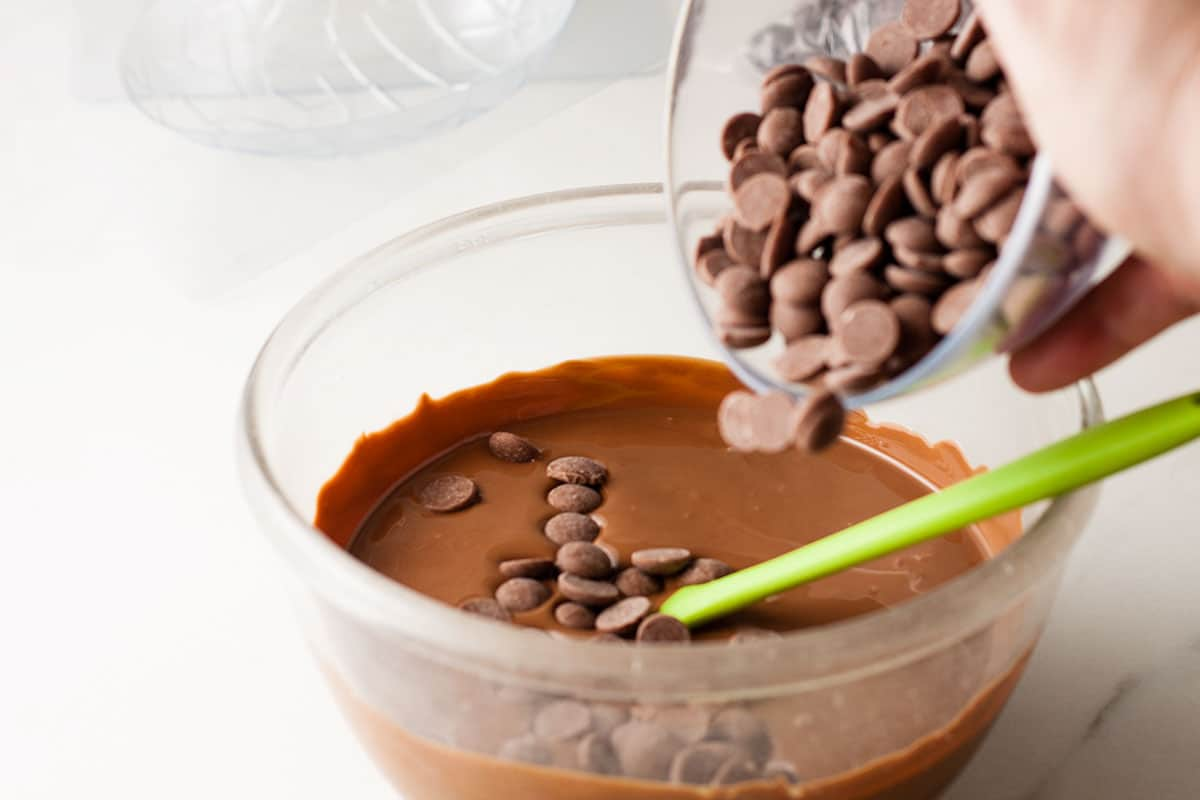 Bowl of melted chocolate with seed chocolate being added.