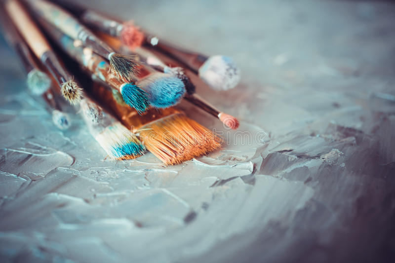 Paintbrushes on artist canvas covered with oil paints. Paint brushes on artist canvas covered with oil paints stock images