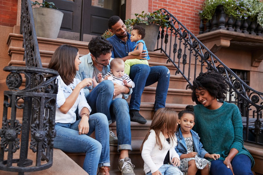 two families with young children sitting on stairs in front of an apartment