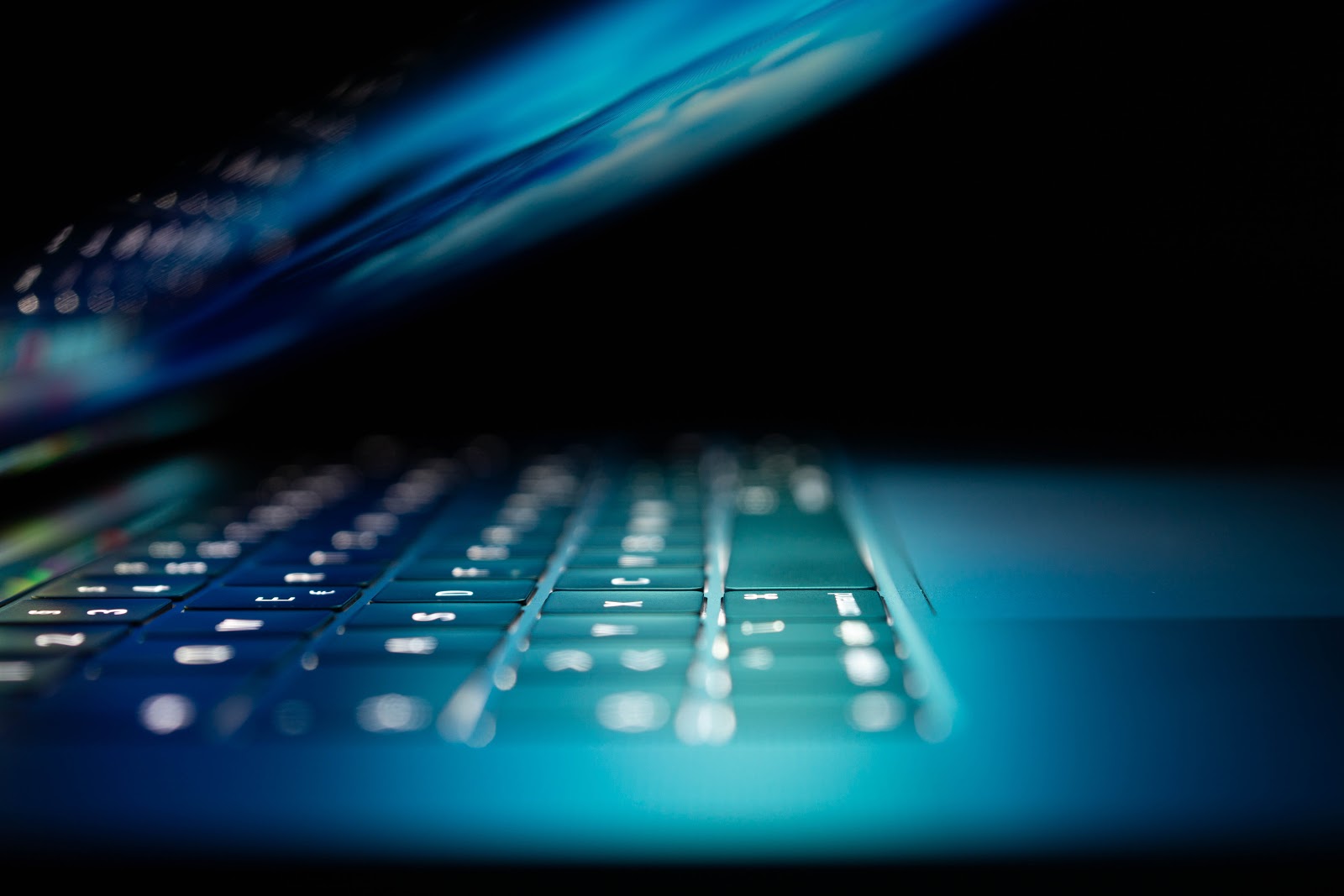 closeup photo of a half-open silver laptop with blue light