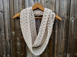 infinity crochet scarf on hanger in front of wooden fence